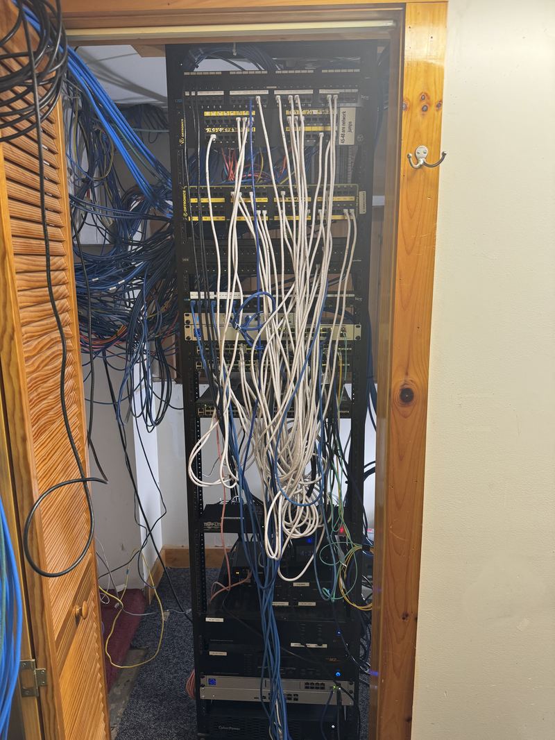 Disorganized data closet with tangled patch cables before CompDAT cleanup